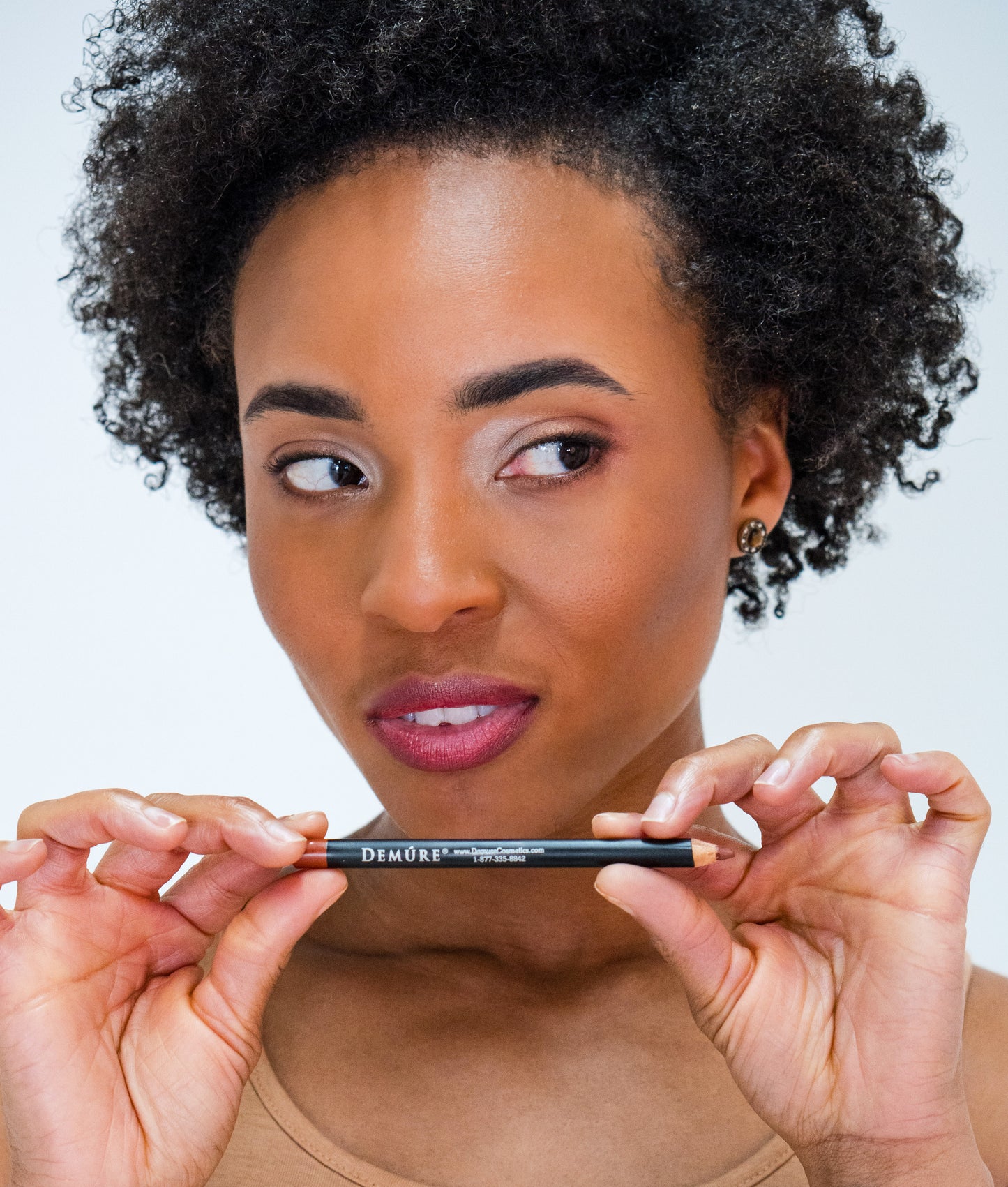 African American woman wearing Coffee Lip Liner Sweetheart Lipstick, holding the pencil just under her lips