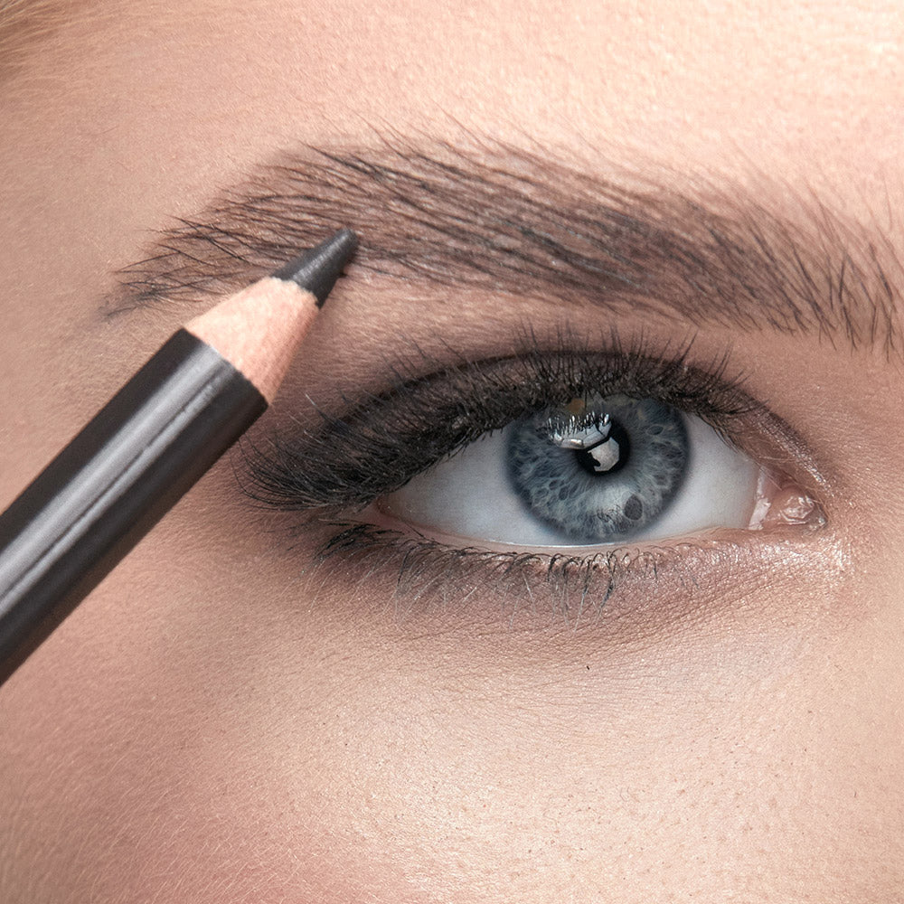 Photo of a woman applying medium brown liner color to her brow using Demure's brow liner product