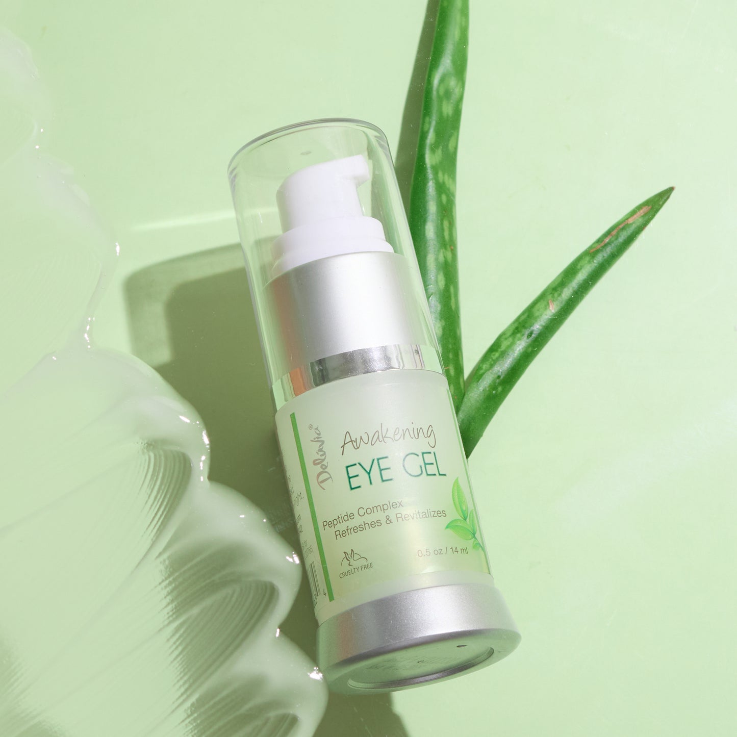 A pump bottle of Deluvia Awakening Eye Gel on its side with aloe plant leaves under it