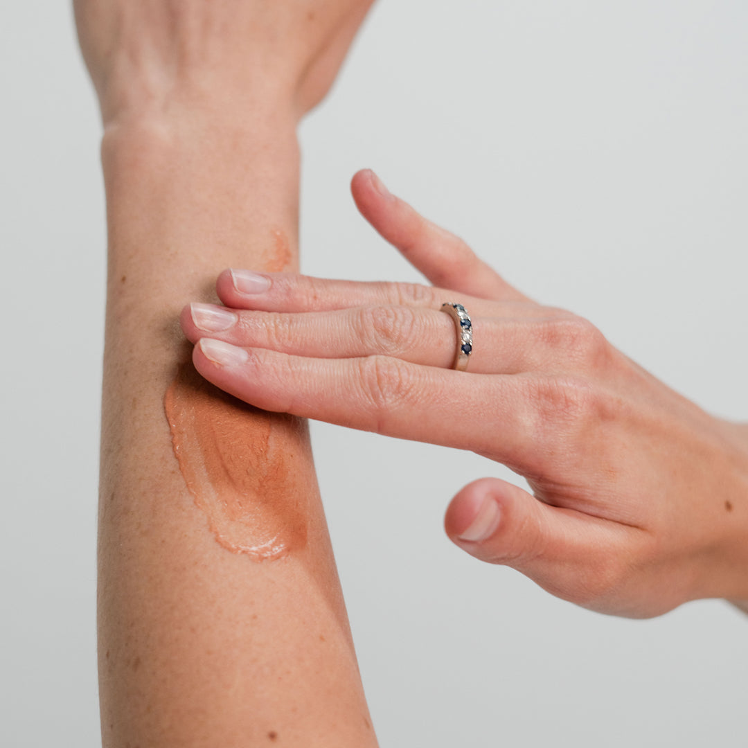 Hand applying a Deluvia bronzing lotion to their arm