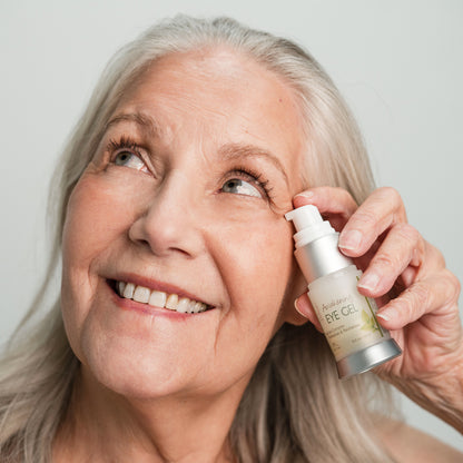 Woman applying eye gel to her face with a neutral background