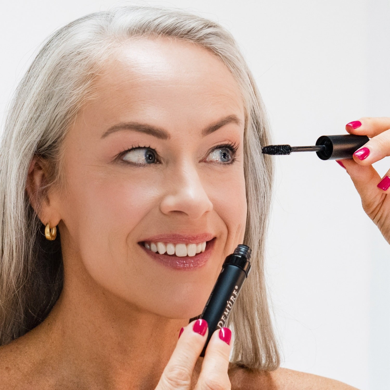 Woman applying Demure Black Mascara