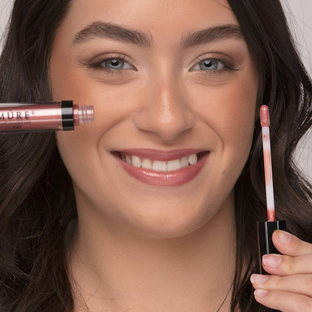 Woman wearing Demure Bronze Glow Lip gloss, holding an open tube and applicator.