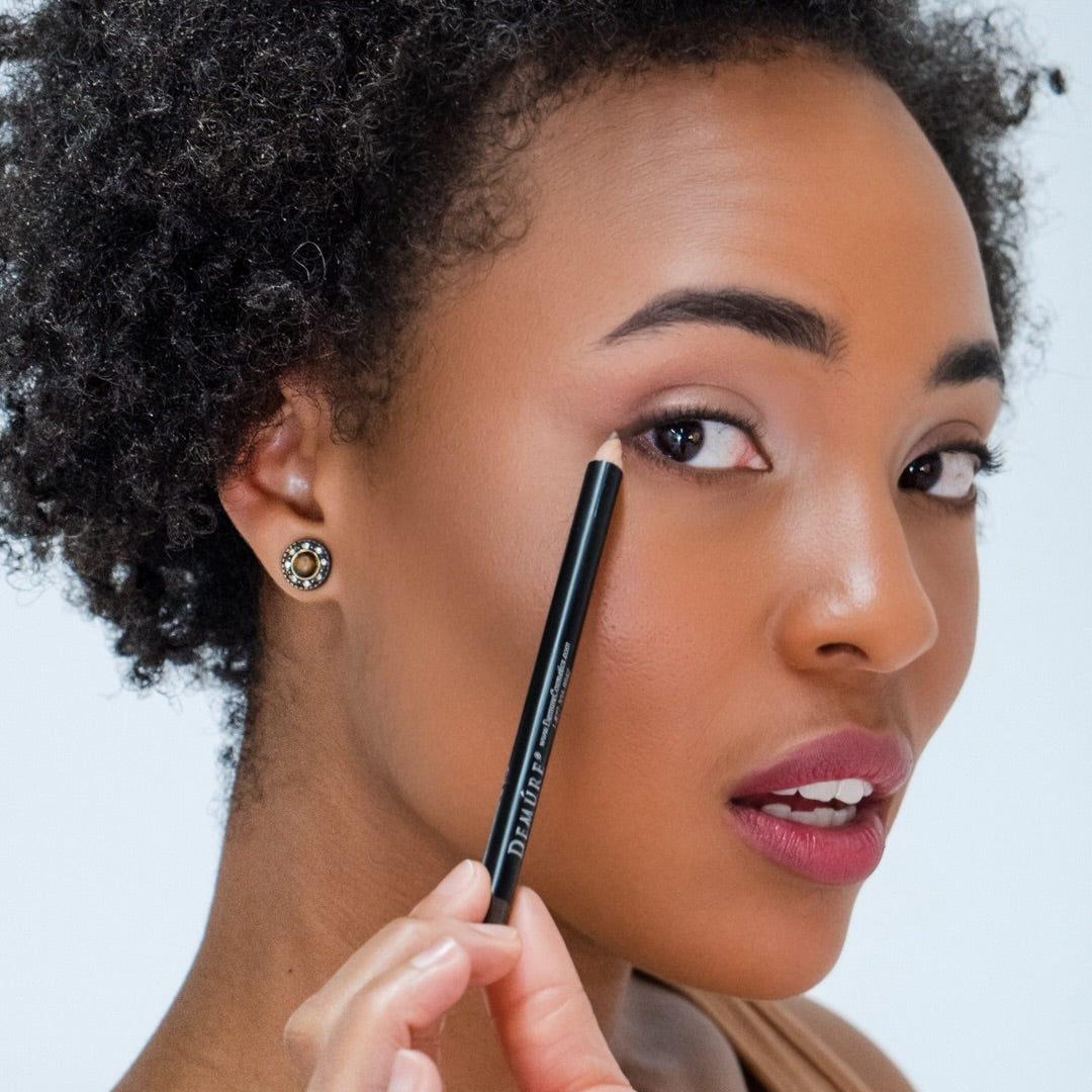 African American woman applying Demure Earth 47 Eye Liner with a pencil near her eye