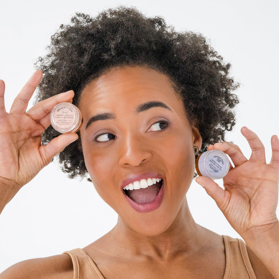 Woman wearing Demure Purple Crush eyshadow and holding a jar of it in her fingers