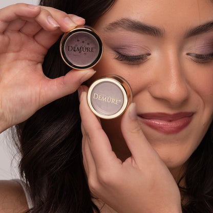 Woman wearing Demure eye colors Spring Fever and Plum, holding eye color jars in her hands