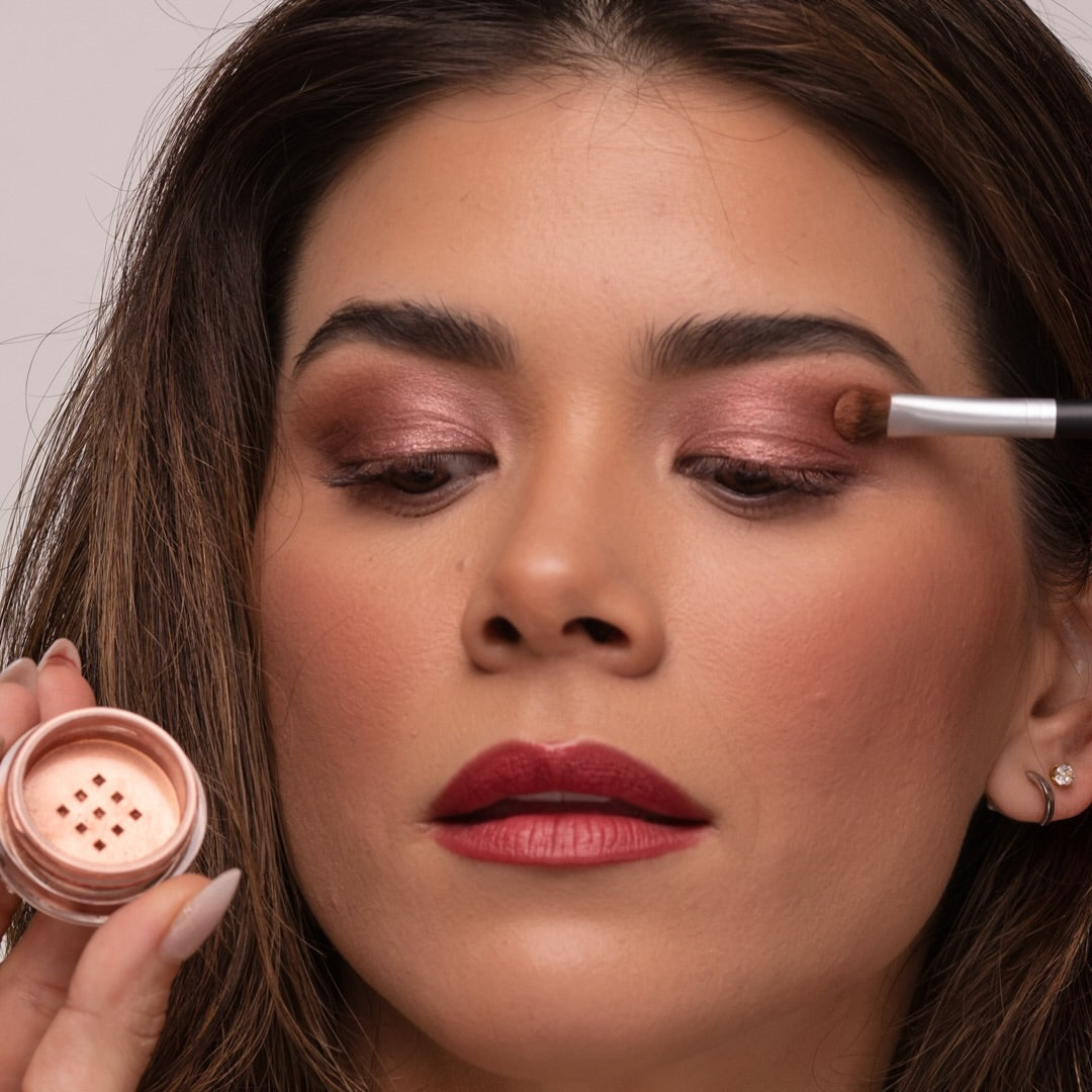 Woman applying Demure eye colors Sienna and Taupe, with a brush holding the eye color jar