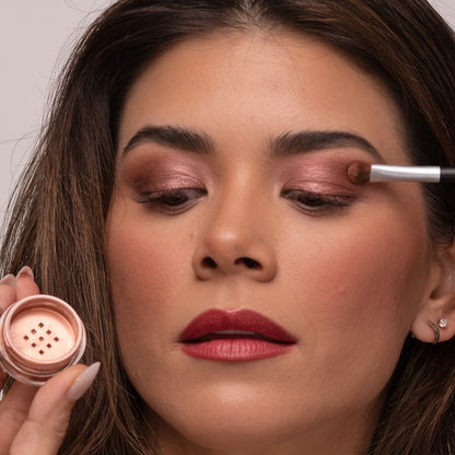 Woman applying Demure eye colors Sienna and Taupe, with a brush holding the eye color jar
