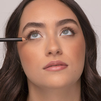 Woman applying Demure Earth Eye Liner pencil, looking up