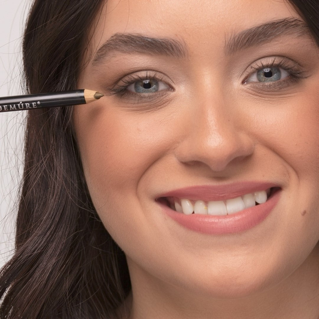 Woman applying Demure Sage Eye Liner pencil on her right eye