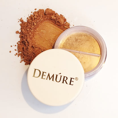 Open container of Demure Face & Body Bronzer with a swatch of shimmery powder
