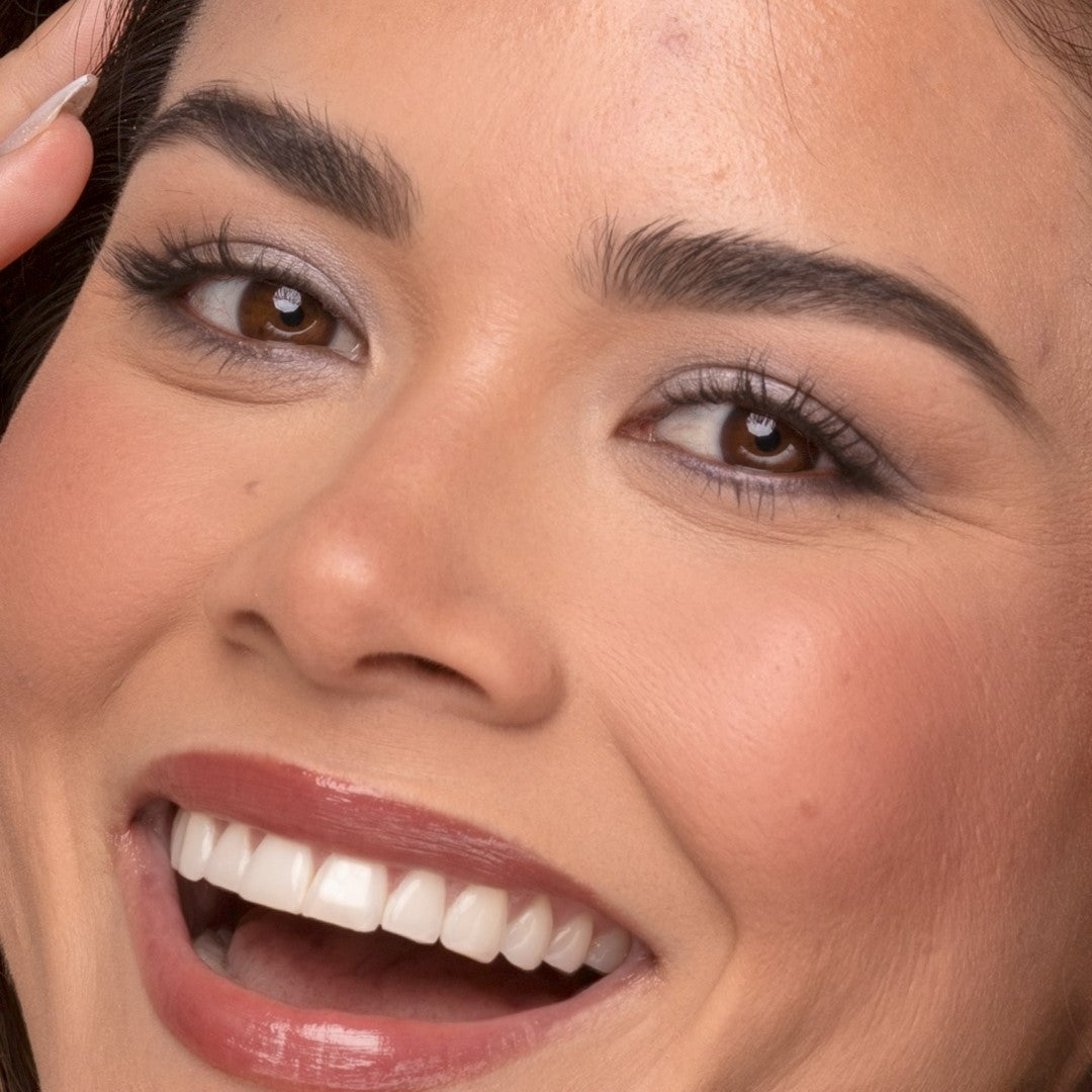 Close-up of a woman's face waring Demure High Definition Black Mascara with a focus on her eyes and smile.