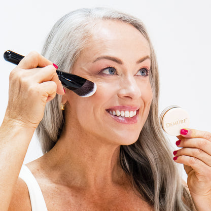 Woman applying Demure Hint of Pink Blush with a Sculpting Contour Brush