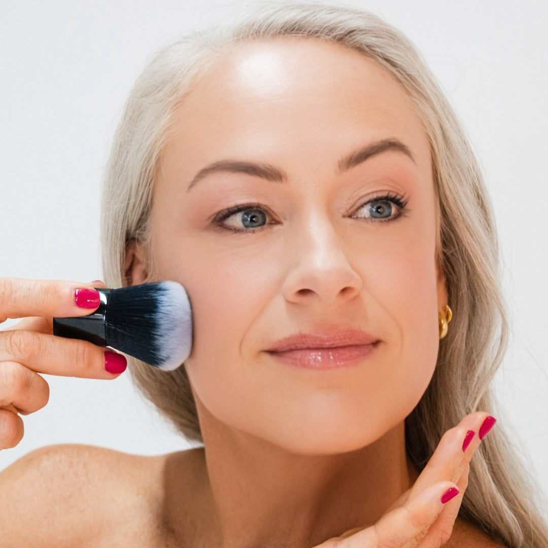 Woman applying Demure Light Foundation with a Kabuki Brush
