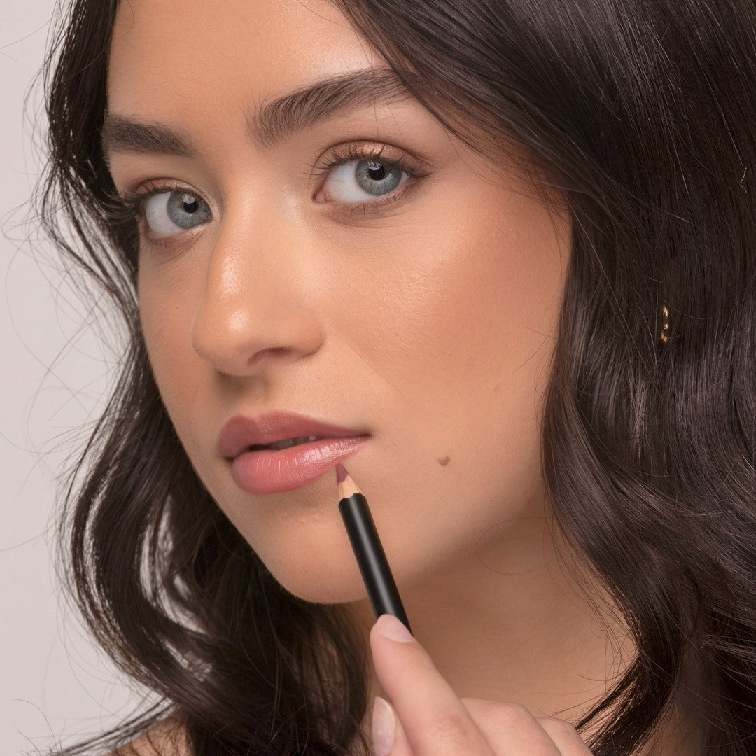 Woman wearing Demure Antique Rose Lip liner with the pencil outlining her lower lip.