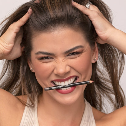 Woman holding a Demure Sable Brown Lip Liner pencil to her mouth with a neutral background