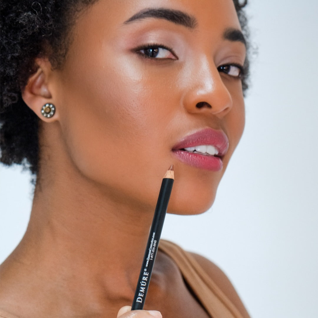 African American woman wearing Demure Lip Liner Sable Brown 46 and holding the pencil near her lower lip.