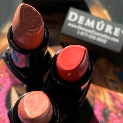 Lifestyle image showing three open Demure lipsticks