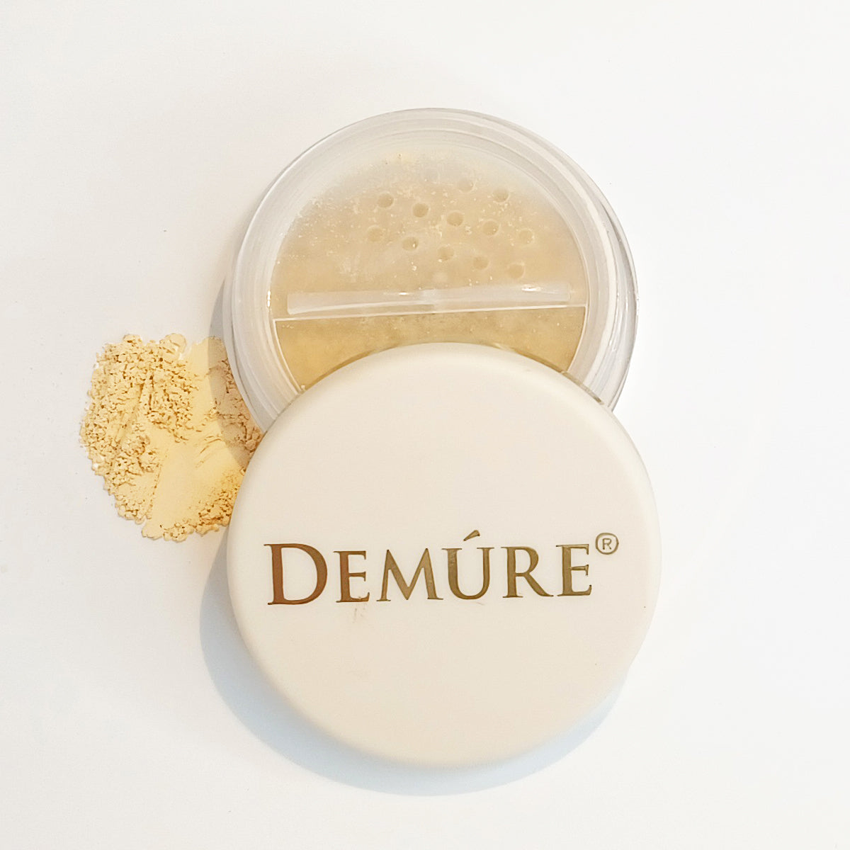 Open container of Demure Original Concealer with a swatch of the minerals on a light background