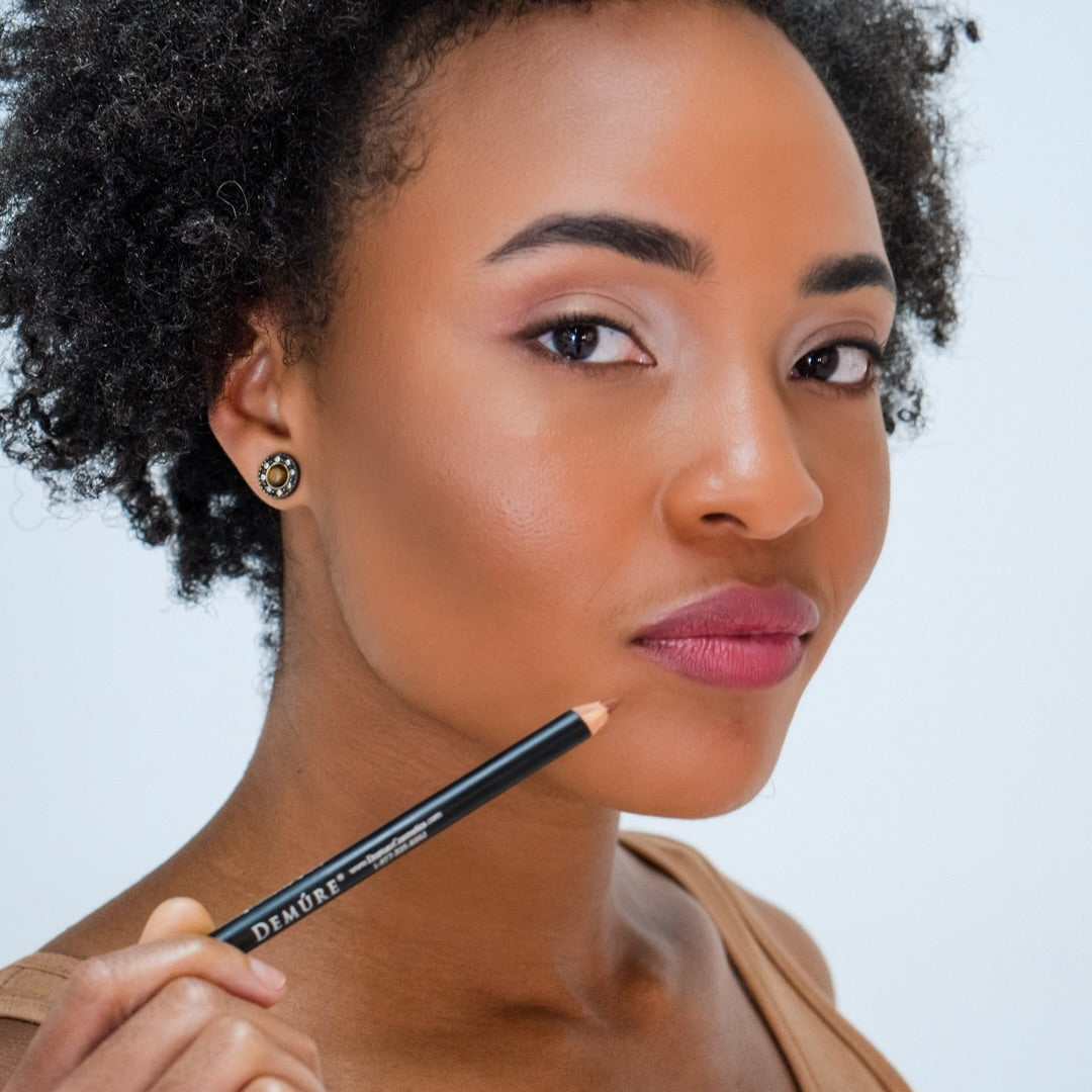 African American woman wearing Demure Lip Liner Sable Brown 46 and holding the pencil beside her lips