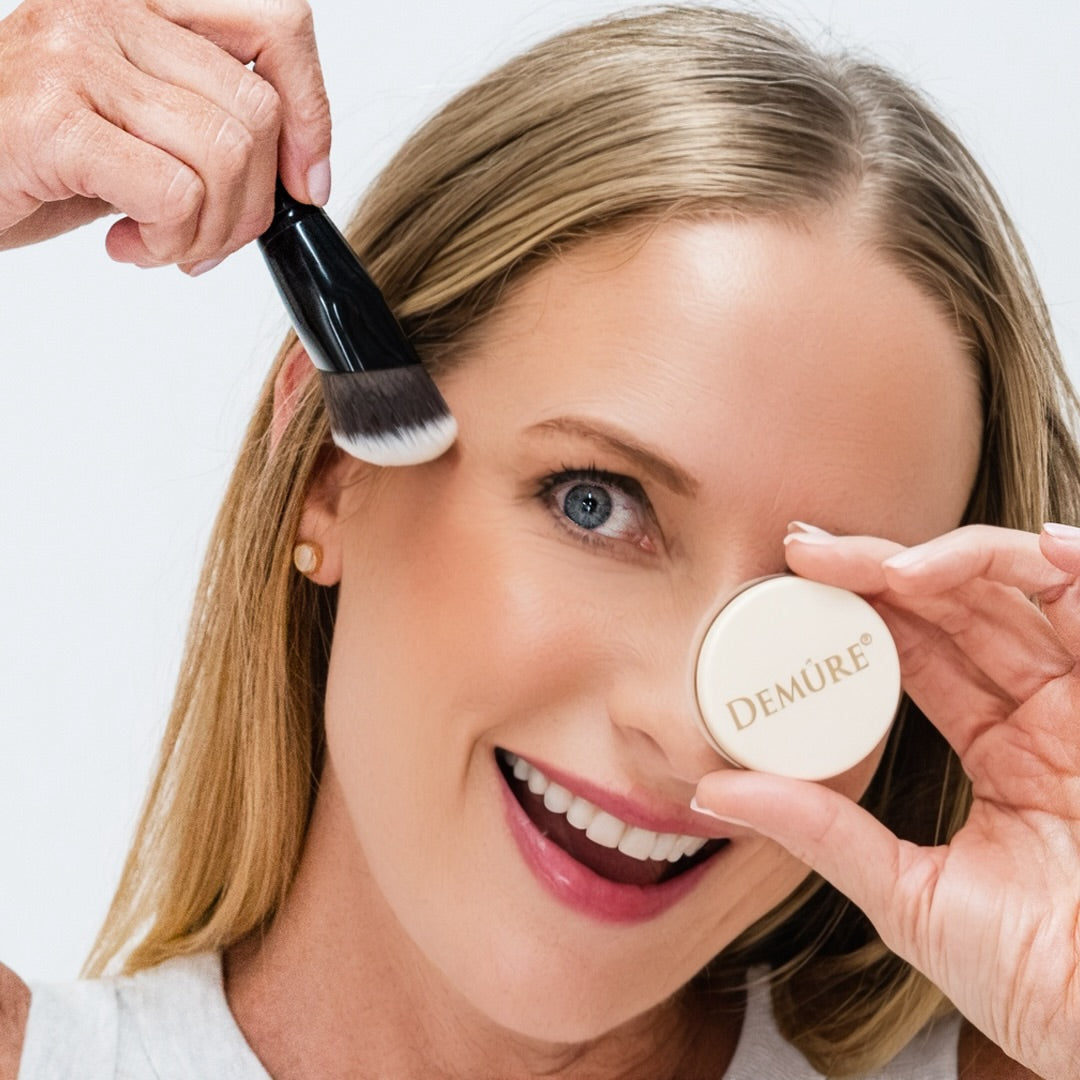 Woman wearing Demure Satin Rose Blush, and holding a jar and a Contour Brush near her cheek