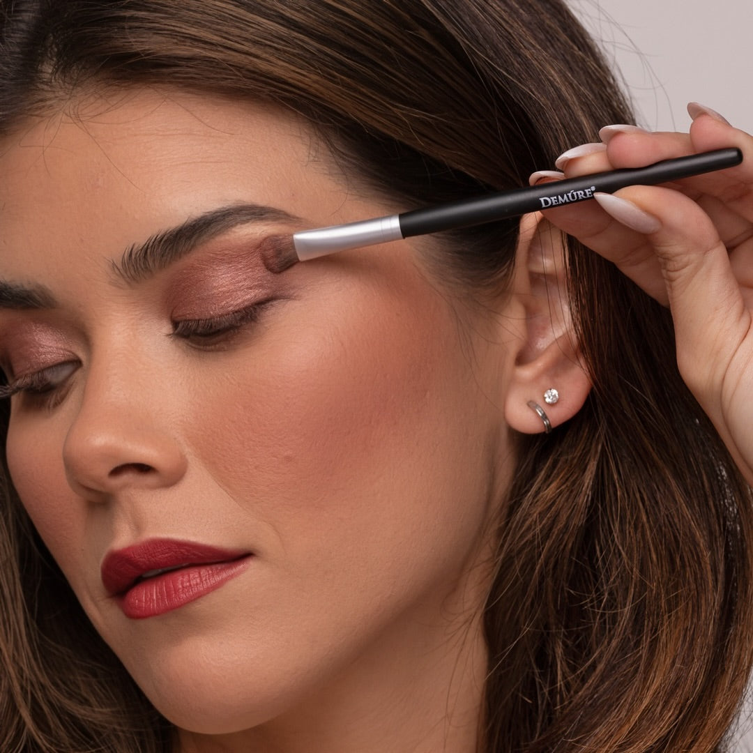 Woman applying makeup with a Demure Eye Shadow brush, close-up of face