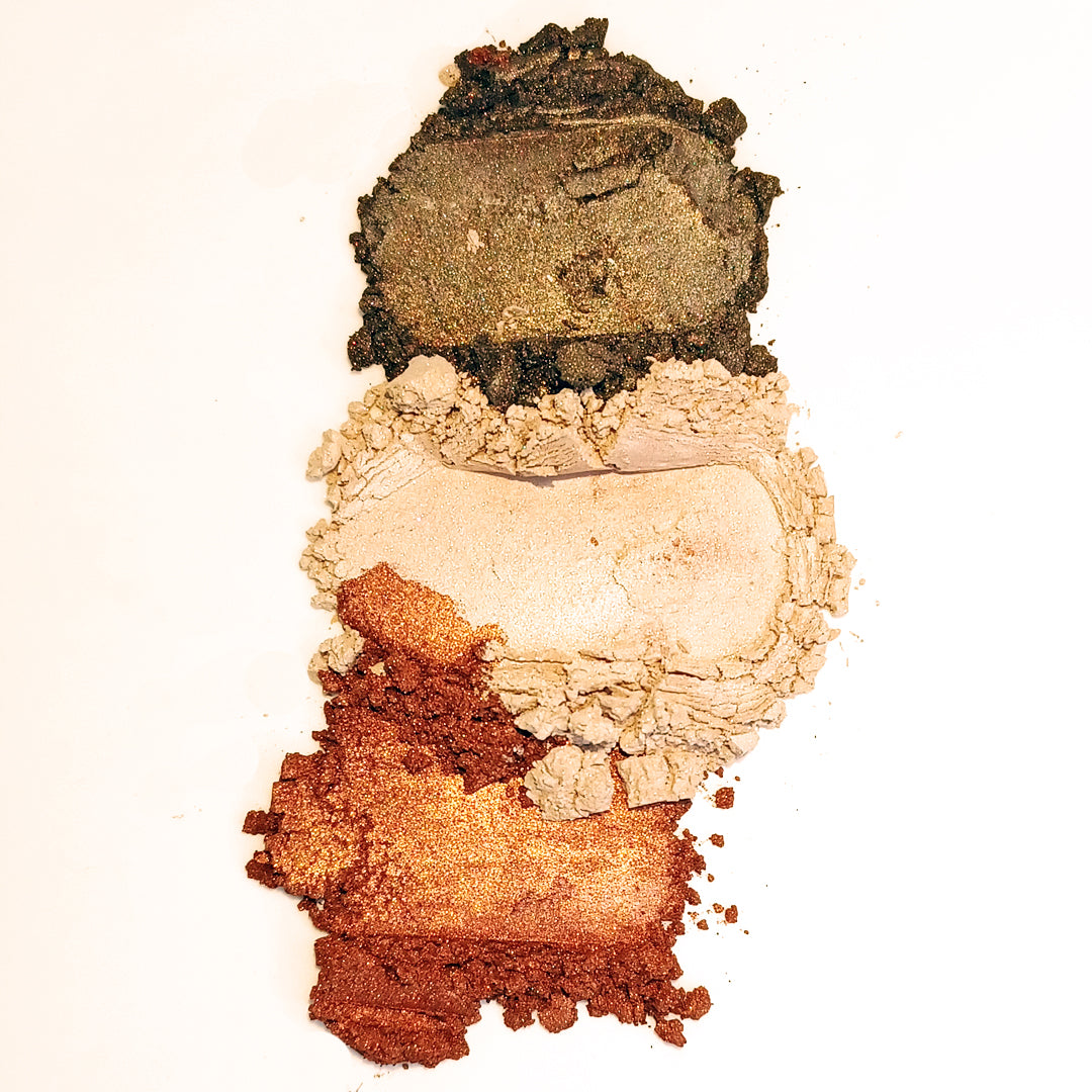 Stack of multicolored makeup powders Demure Brownstone Sparkle, Naked Glow and Sienna on a white background
