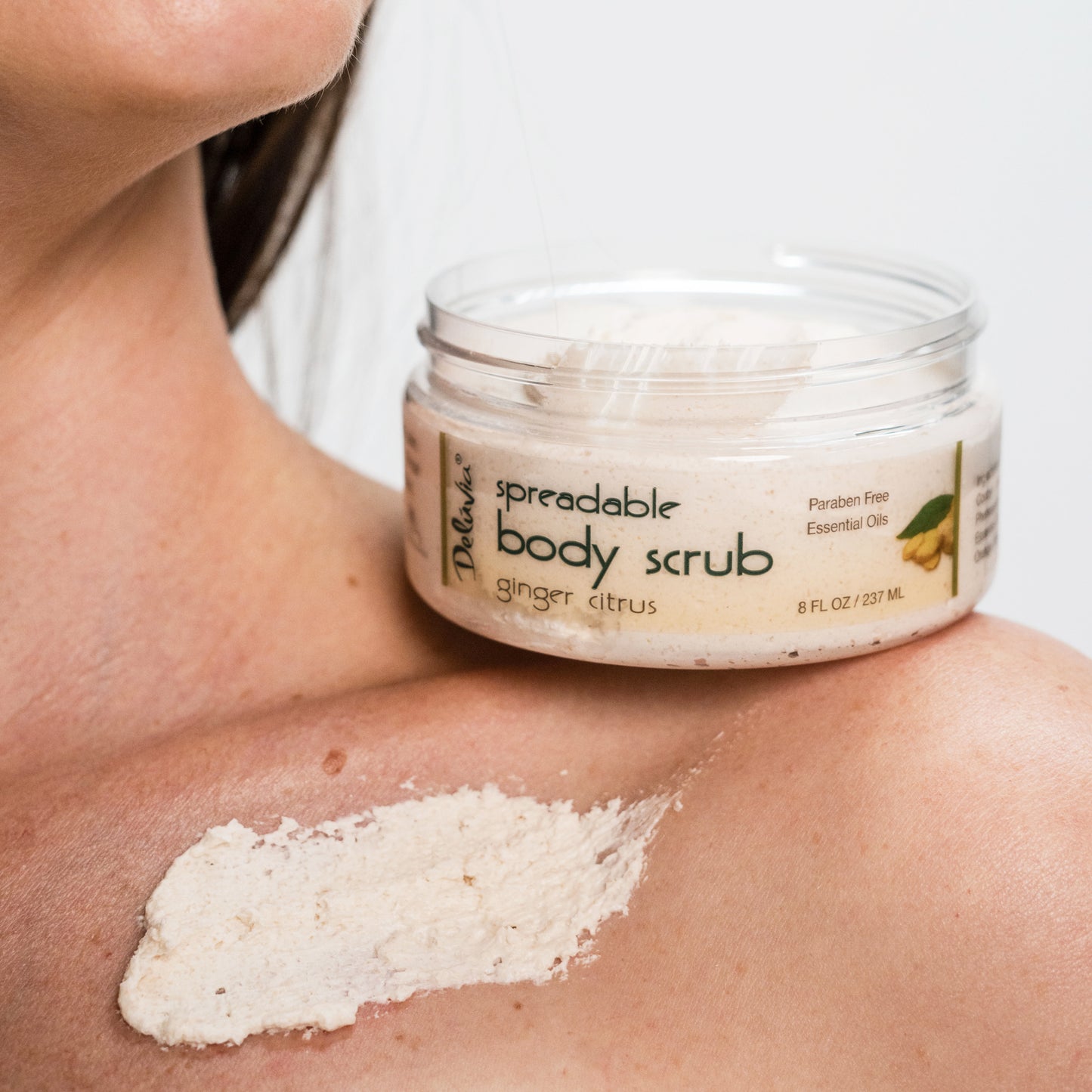 Woman with Deluvia Ginger Citrus Body Scrub sitting on her shoulder with s smear of scrub