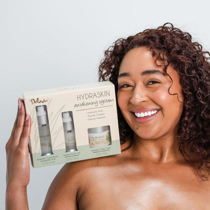 Smiling African American woman holding Deluvia HydraSkin Awakening Anti-Aging System on her shoulder