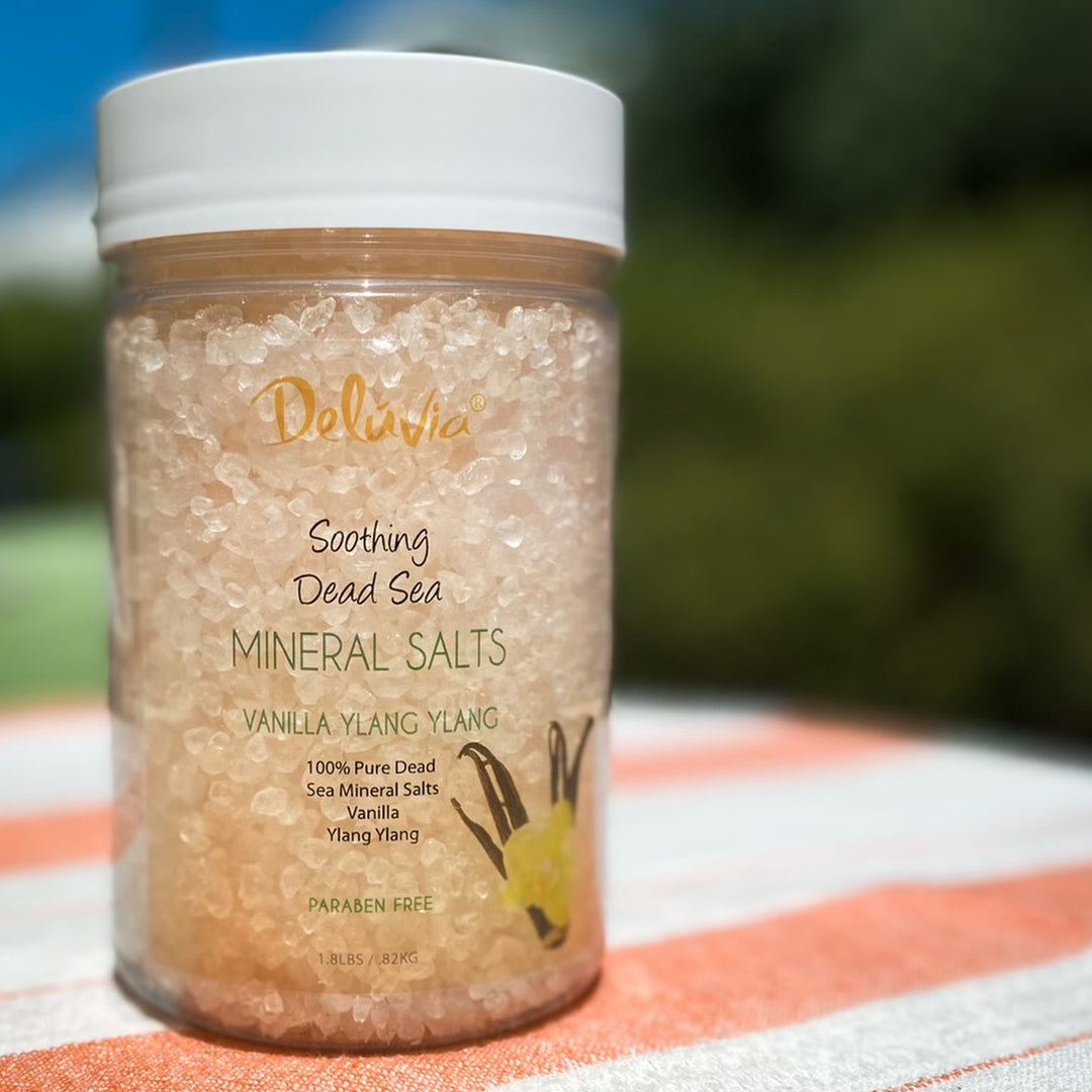 Jar of Deluvia Soothing Dead Sea Mineral Salts on a striped towel with a blurred natural background