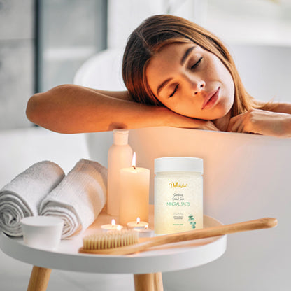 Woman relaxing with a jar of Deluvia mineral salts, candles, and towels in a bathroom setting.
