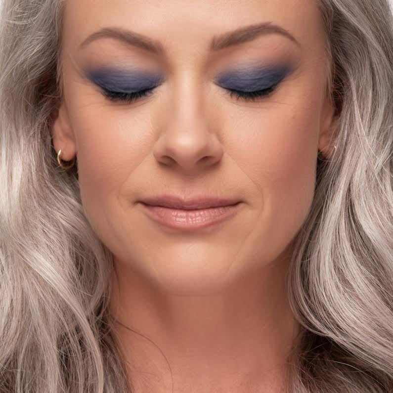 Close-up of a woman with her eyes closed wearing Demure Midnight Blue eye color.