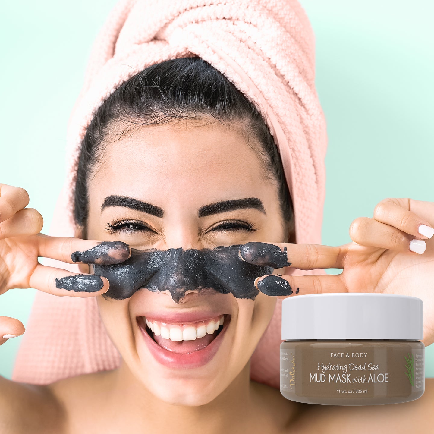 Young woman smiling with dead sea mud mask applied to her face and a jar of Deluvia Hydrating Dead Sea Mud Mask with Aloe in the foreground