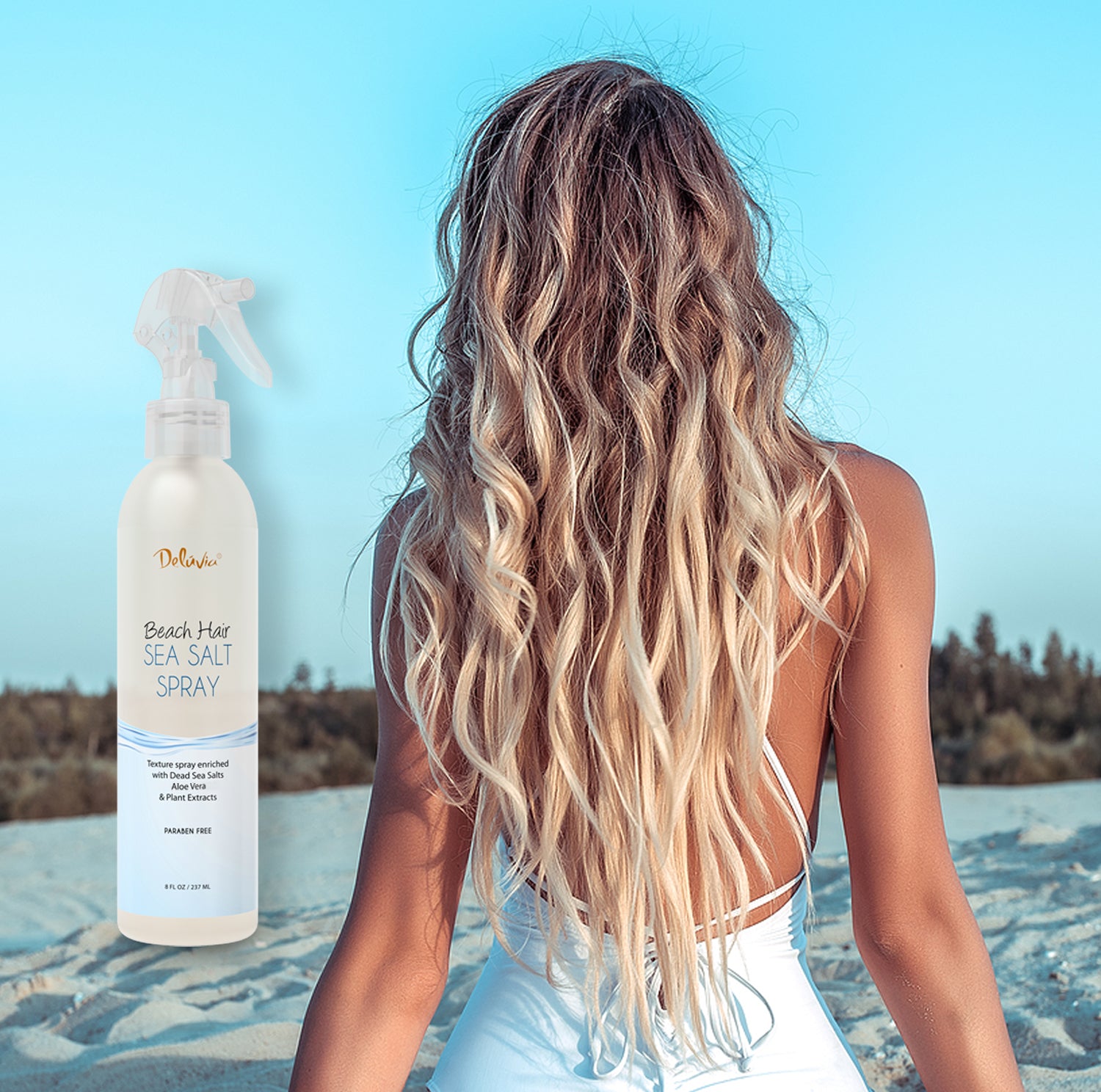 Photocomposition showing a young blonde woman facing a sand dune during the day, with an inclusion of a spray bottle of Deluvia's Beach Hair Sea Salt Spray