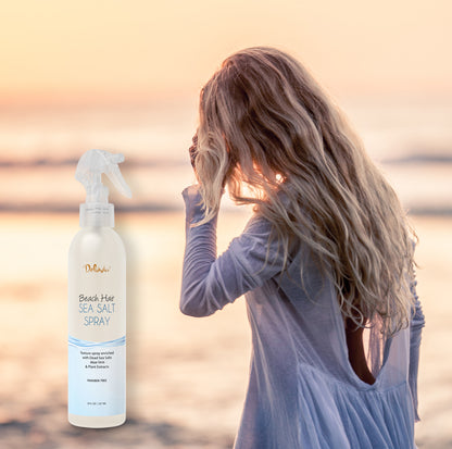 Photocomposition showing a young blonde woman walking on the sea shore at sunset, with an inclusion of a spray bottle of Deluvia's Beach Hair Sea Salt Spray