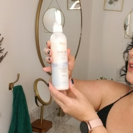 Video clip of a dark-haired woman explaining how she applies the Deluvia Beach Hair Sea Salt Spray product to her hair and the happy result