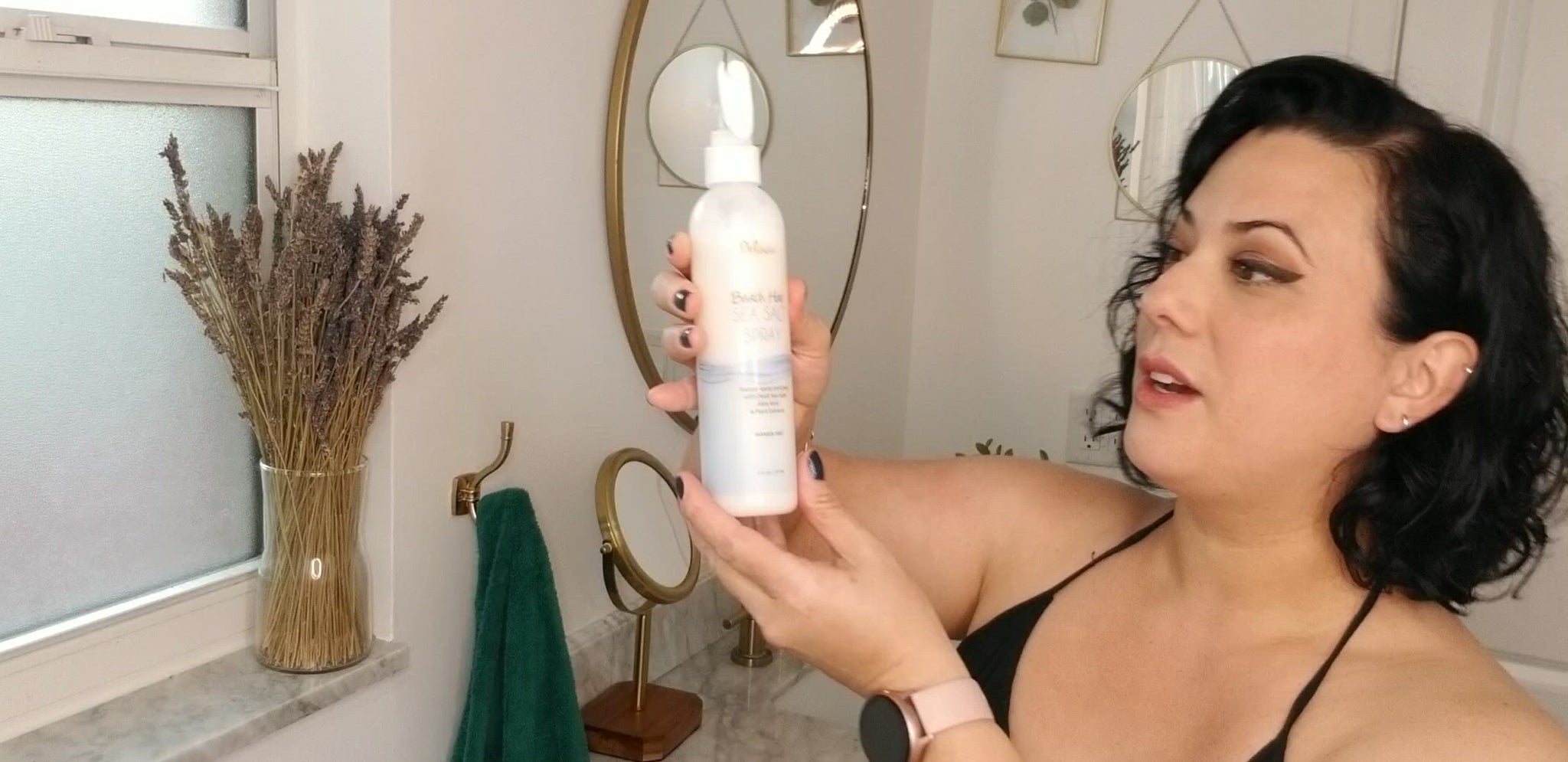 Video clip of a dark-haired woman explaining how she applies the Deluvia Beach Hair Sea Salt Spray product to her hair and the happy result