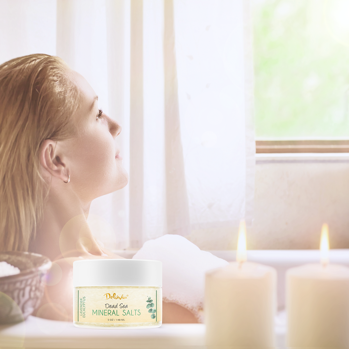 Photo of a woman in a bathtub looking at a window, with a jar of Deluvia's Lavender Eucalyptus Dead Sea Mineral Salts in the foreground