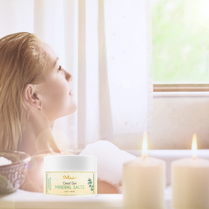 Photo of a woman in a bathtub looking at a window, with a jar of Deluvia's Lavender Eucalyptus Dead Sea Mineral Salts in the foreground