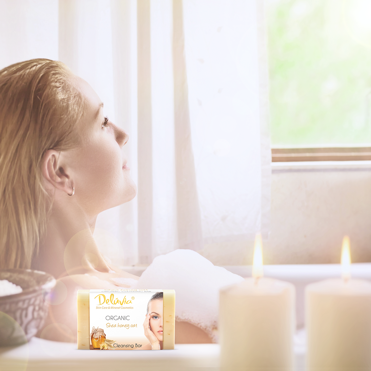 A woman in a bubble bath with candles and a bar of Deluvia soap.
